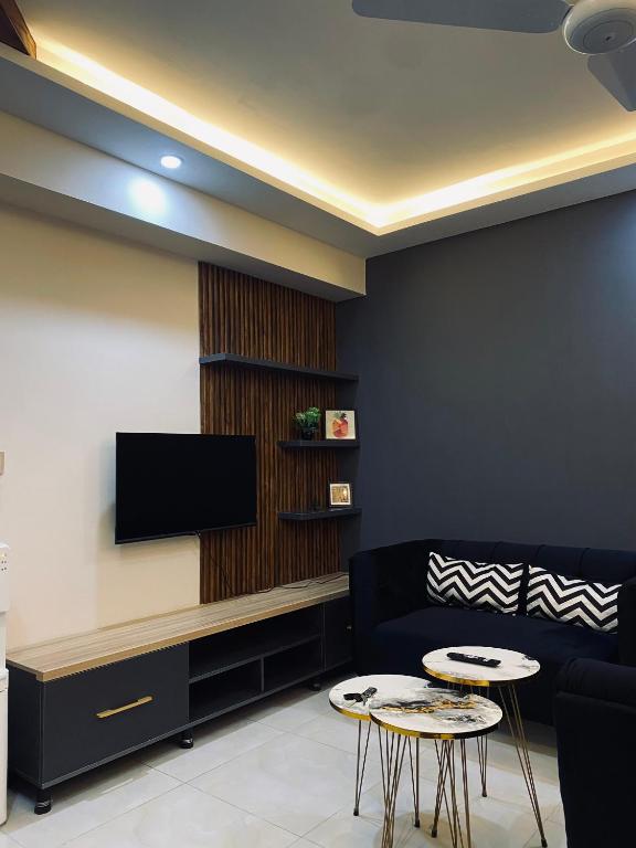 a living room with a couch and a tv and two tables at Luxury, Modern & Central Apartment Islamabad, with Gym, Near Motorway & Airport in Islamabad