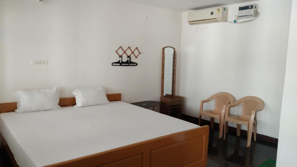 a bedroom with a bed and two chairs at Rainbow Guest House in Mahabalipuram