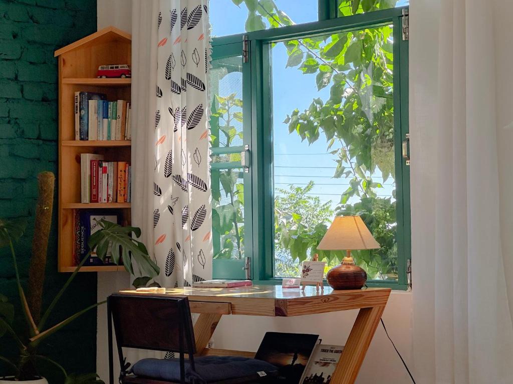 einen Schreibtisch mit einer Lampe vor einem Fenster in der Unterkunft Cottage Story Bir in Bir