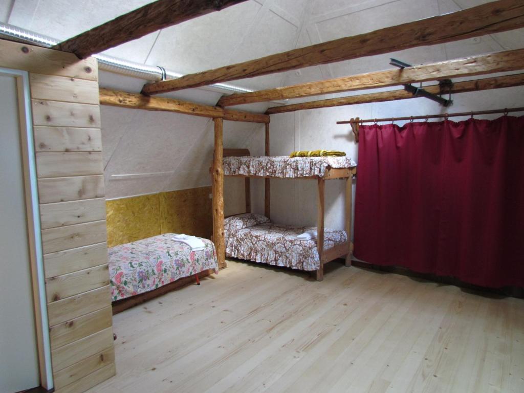 um quarto com 2 beliches e uma cortina vermelha em Joe's Place em Log pod Mangartom