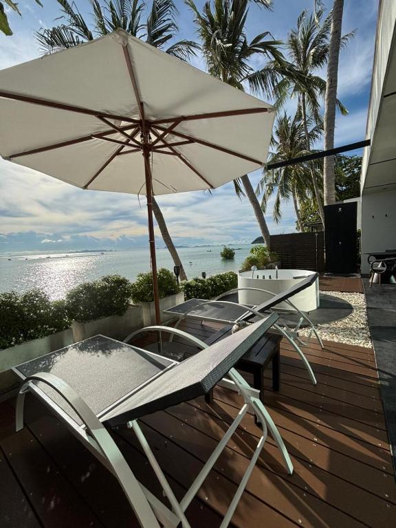 a table and chairs with an umbrella on a deck at Villa Mandi in Ban Thong Phlu