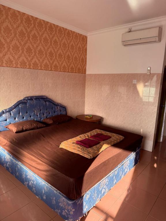 a bedroom with a large bed with a blue headboard at Cempaka 2 Homestay in Legian