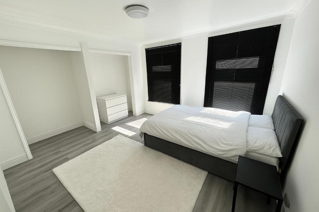 a white bedroom with a bed and two windows at Charming 3 Bed Home Stay in Plumstead
