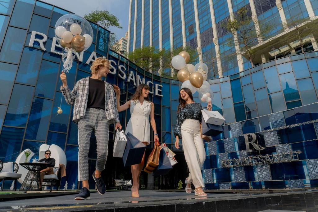 Tres personas caminando frente a un edificio con globos. en Renaissance Bangkok Ratchaprasong Hotel, en Bangkok