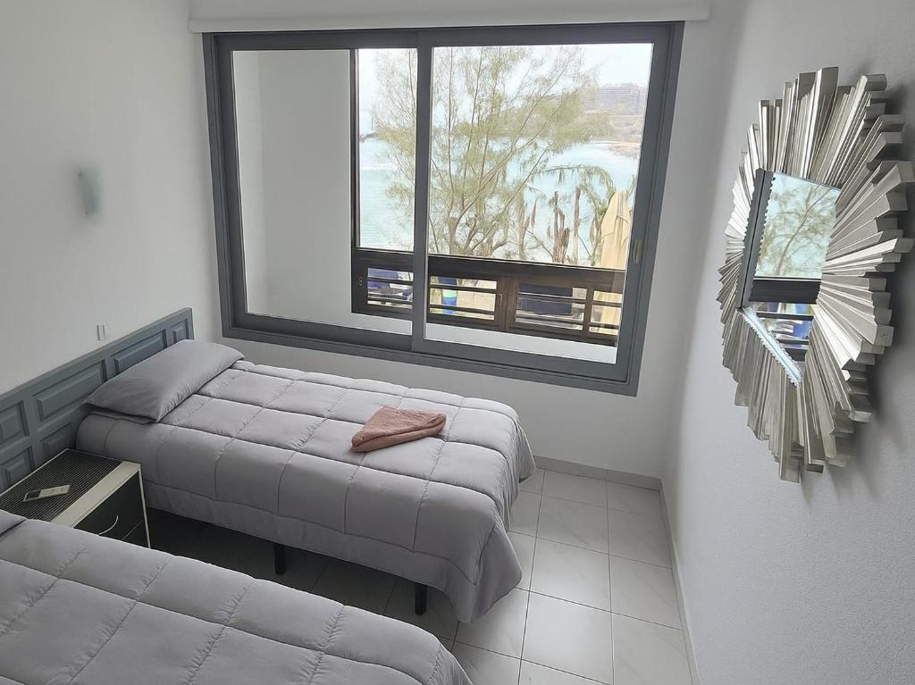 a small room with two beds and a window at Beachfront Patalavaca in Patalavaca