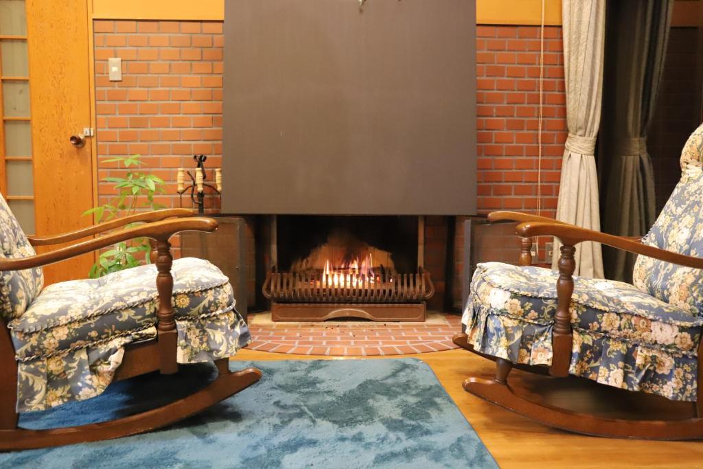 a living room with two chairs and a fireplace at ～みらい荘～　天然温泉付き一日一組様限定の６４坪広々民泊別荘 in Kirishima