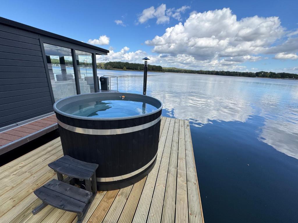 a large tub sitting on a dock on a body of water at Houseboat Marina Mookerplas with XL Hot Tub | 4 - 6 people in Middelaar
