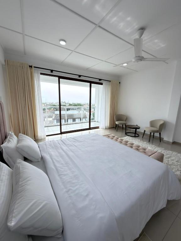a large white bed in a room with a large window at The Altura Apartment in Mount Lavinia