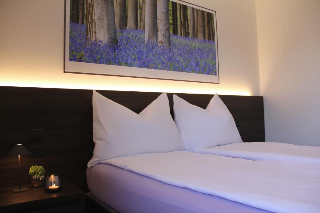 a bedroom with two beds with white pillows and a painting at LA MUELE Affittacamere in Gemona del Friuli