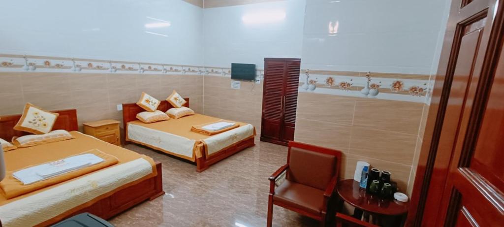 a hotel room with two beds and a chair at Van tan in Kon Plong