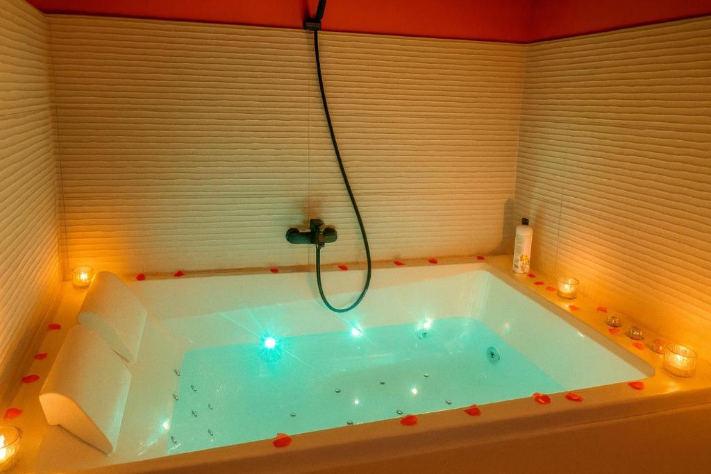 a bath tub with a shower in a room at Studio romantique avec baignoire balnéothérapie duo et jardin proche de Colmar et Kaysersberg pour 2 personnes in Lapoutroie