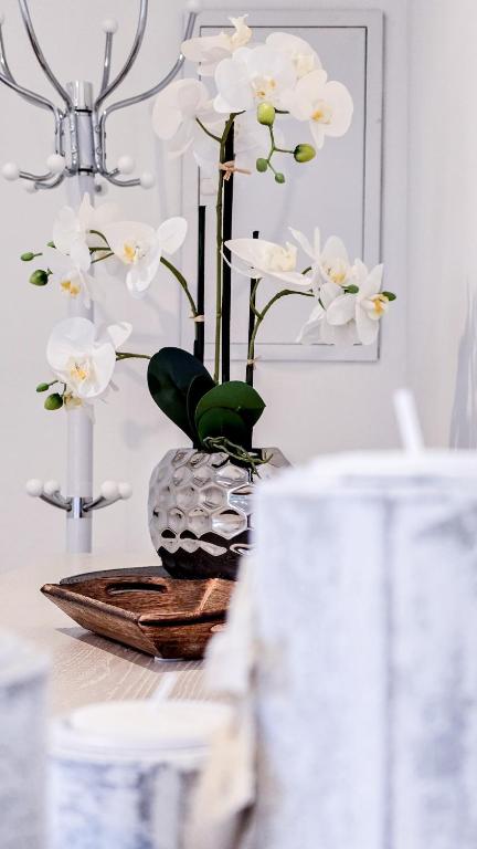a table with a vase with white flowers in it at 90m Apartment 5 Schlafplätze in Tostedt