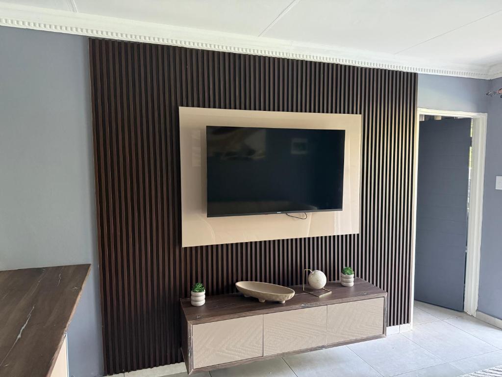 a living room with a television on a wall at UbuntuLifeStyleEstate-Premium Suite in Krugersdorp