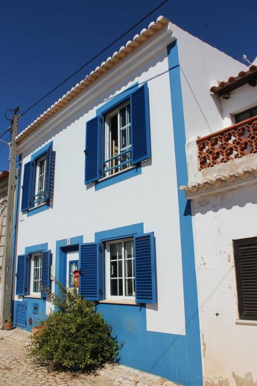 niebiesko-biały budynek z niebieskimi okiennicami w obiekcie Casa dos Coelhos w mieście Barão de São João