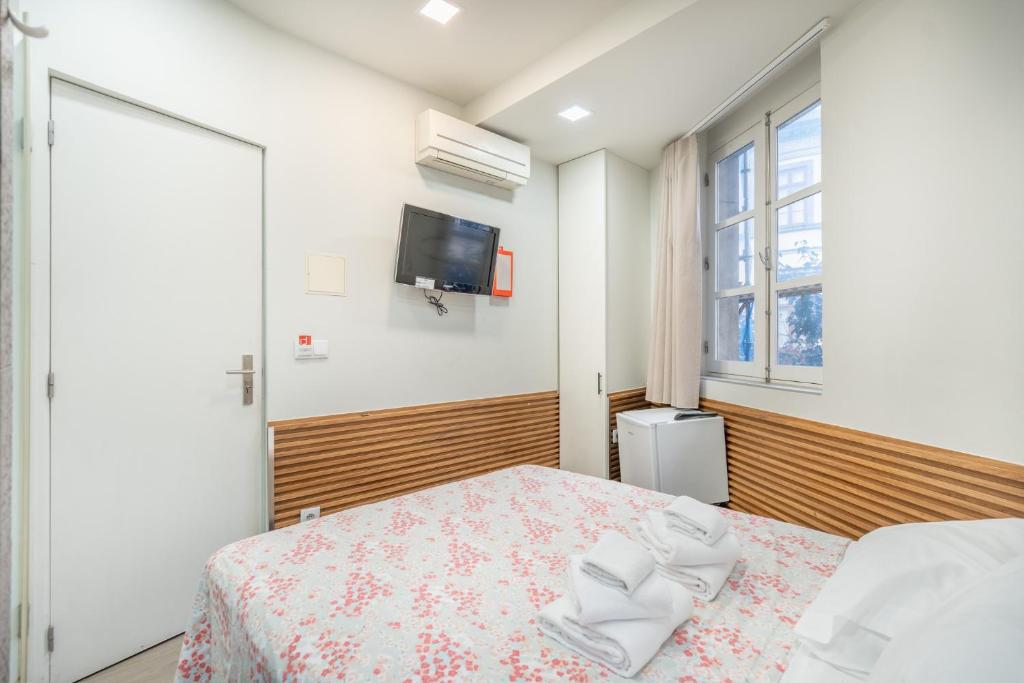 a bedroom with a bed and a tv on the wall at Souto Centro Rooms in Braga