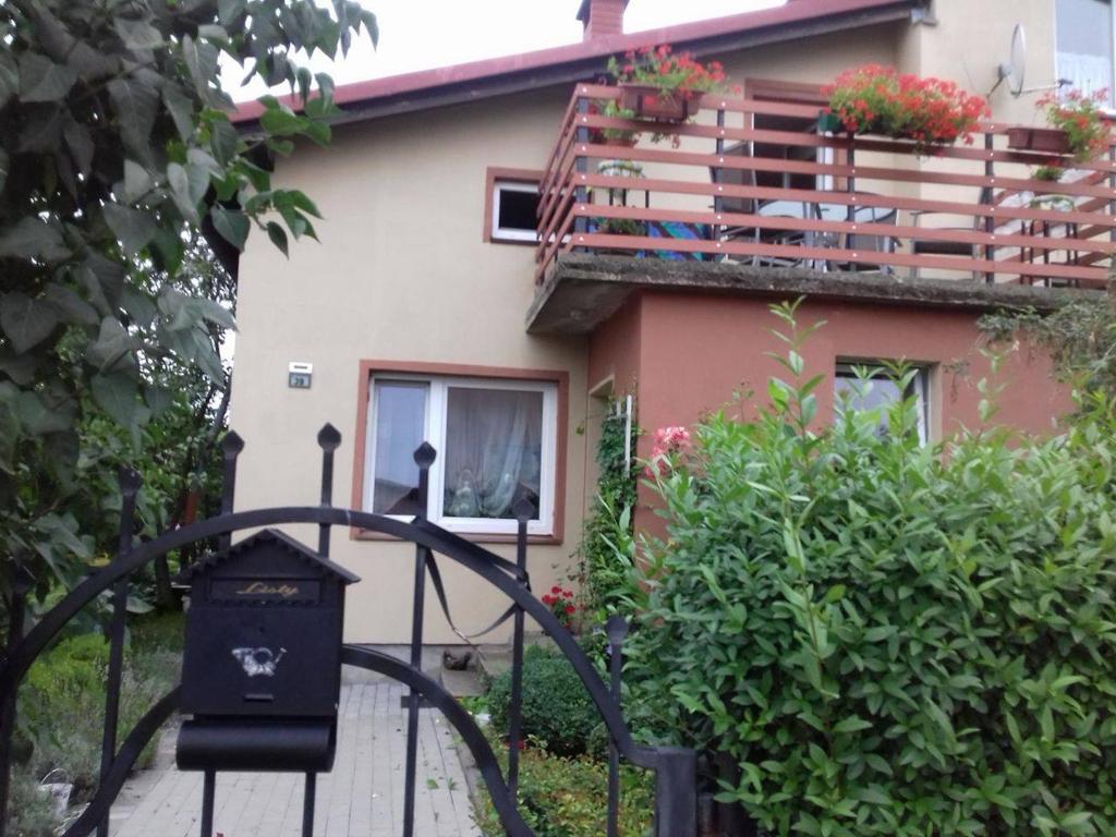 a house with a gate and a balcony with flowers at Noclegi u Lili in Człuchów