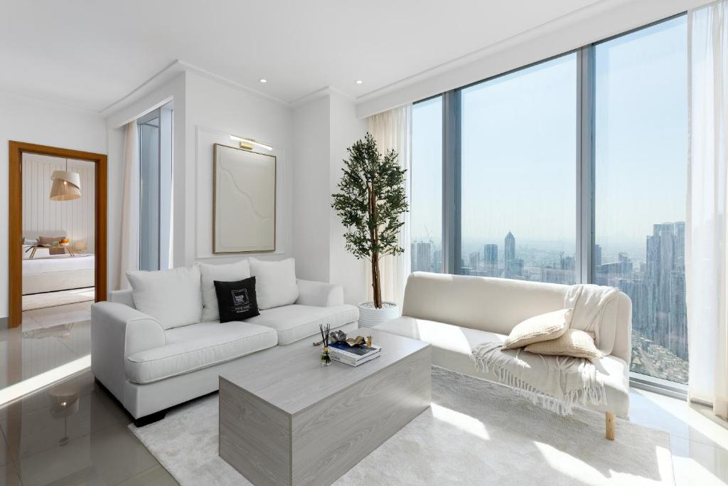 a living room with white furniture and large windows at Maison Privee - City Heights Retreat with Panoramic Skyline Views in Dubai