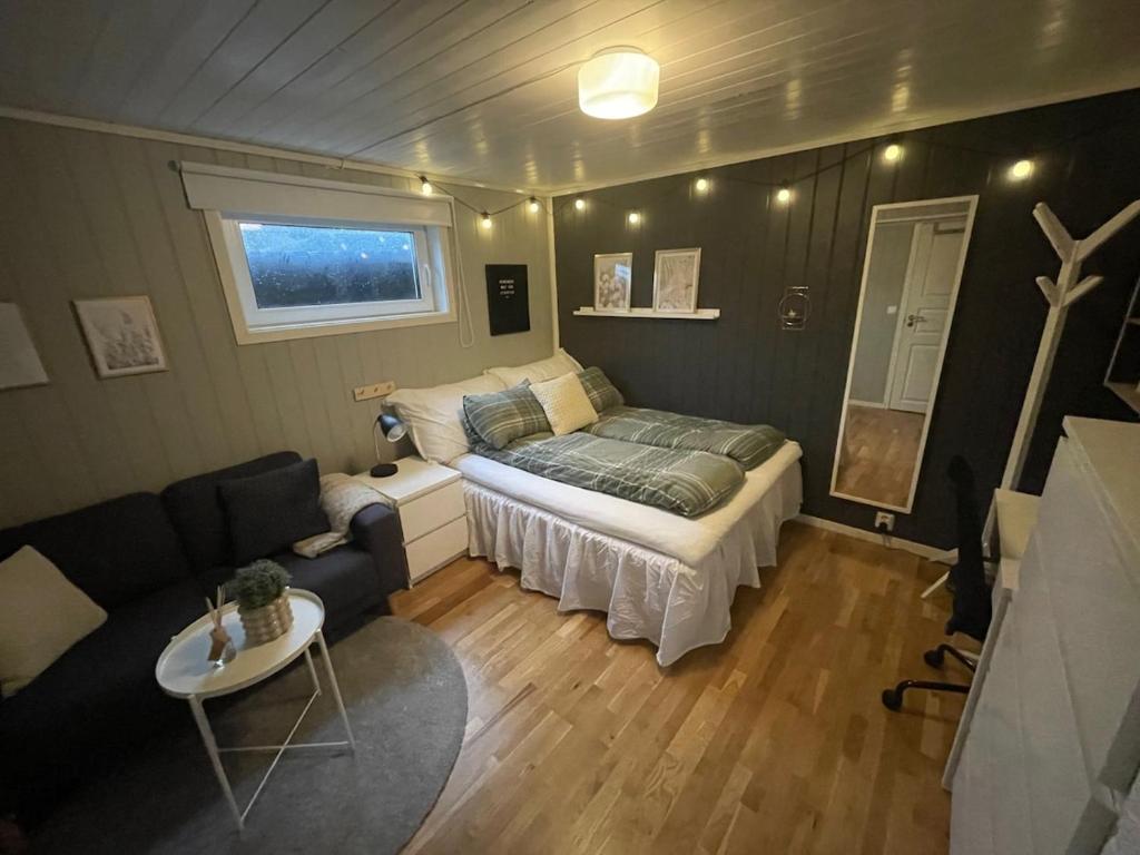 a small bedroom with a bed and a couch at 1 roms kjellerleilighet Norheim, Haugesund in Karmøy