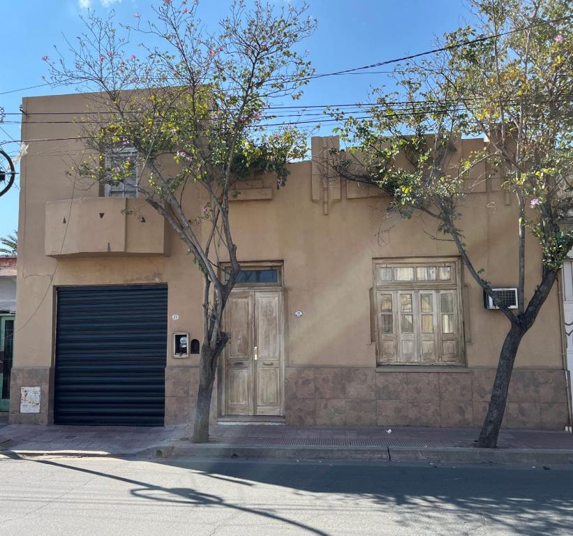 a building with two doors and two trees on a street at Las Marias in San Fernando del Valle de Catamarca