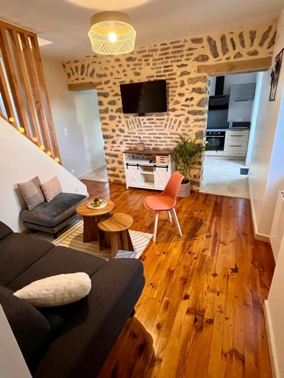 a living room with a black couch and a brick wall at La Maisonnette de Chevannes in Sainte-Magnance