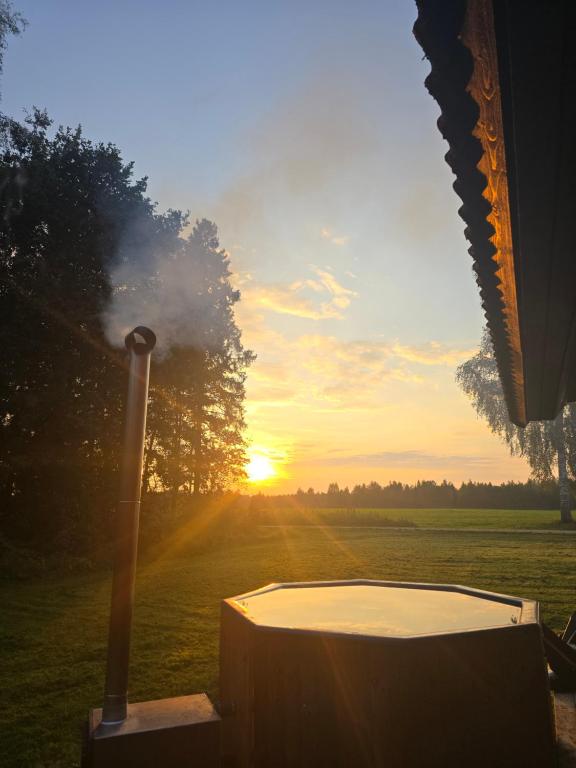 a hot tub in a field with the sunset in the background at Tammetalu puhkemaja 