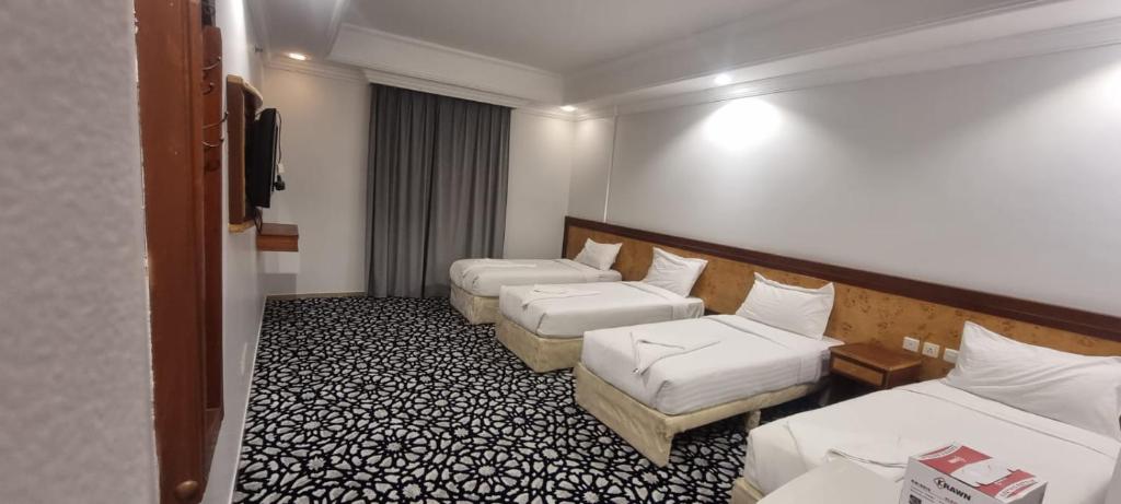 una habitación de hotel con dos camas y un sofá en Durrat Al Talae Hotel, en Al Masfalah