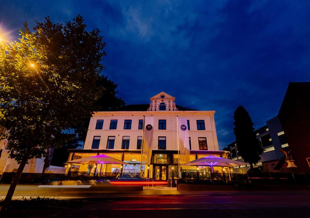 un edificio blanco con sombrillas púrpuras delante en Atlas Hotel, en Valkenburg