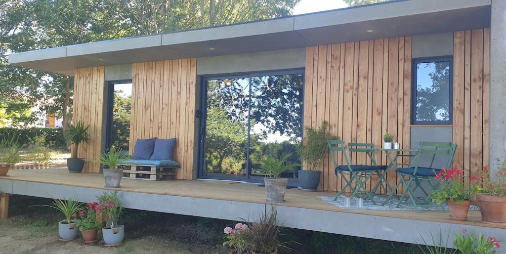 une maison dotée d'une terrasse avec des chaises et une table dans l'établissement Le Cormier lodge, entre Loire et Anjou, à La Chapelle-Saint-Florent