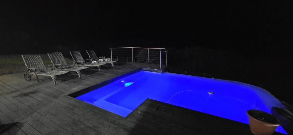 a blue swimming pool at night with chairs around it at Lazey Bazely Beach Cottage in Bazley Beach