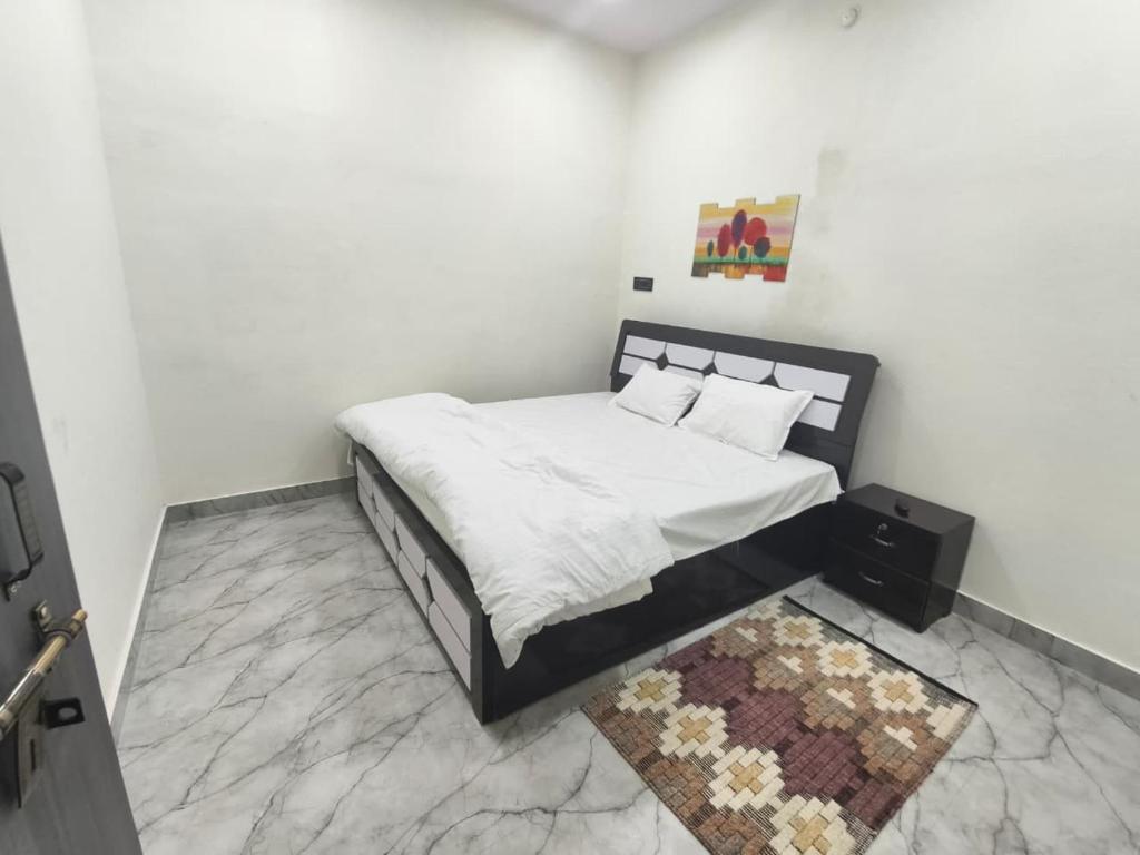 Un dormitorio con una cama con sábanas blancas y una alfombra. en Rainbow Inn, en Varanasi