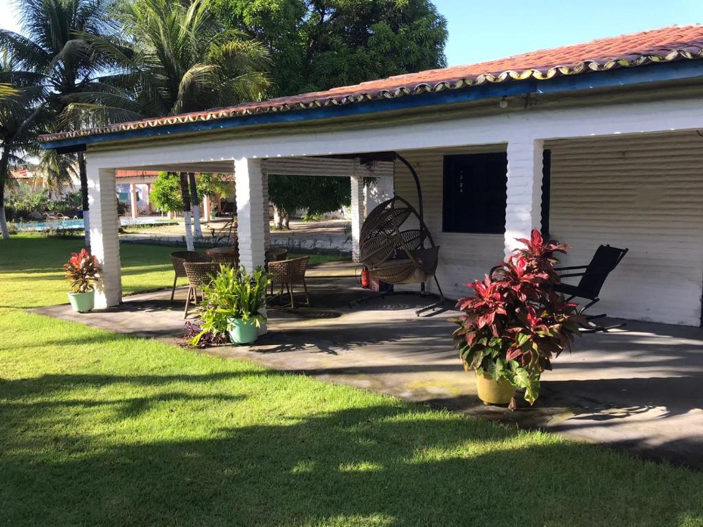 a porch of a white house with chairs and flowers at Sitio Damiana in Paracuru