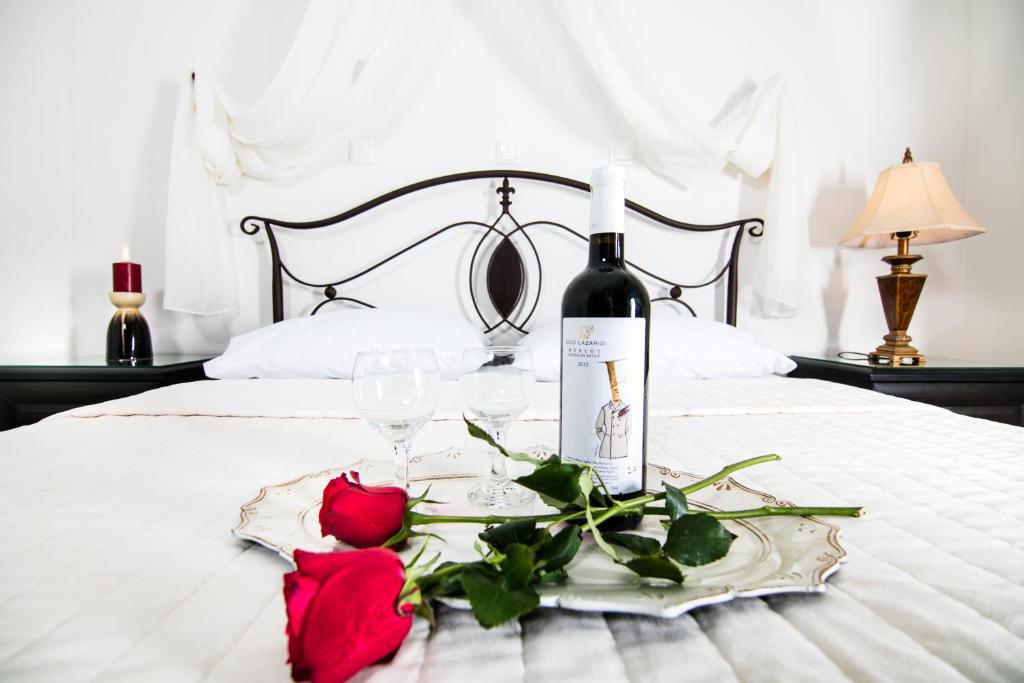 a bottle of wine and two roses on a bed at Niki Apartments in Chrysi Ammoudia