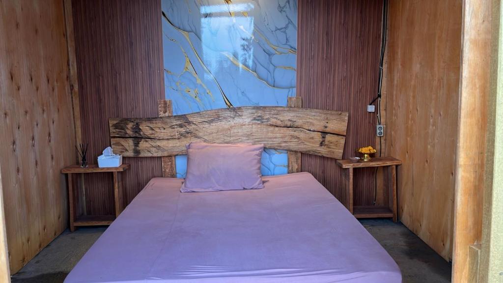 a bedroom with a bed with a wooden headboard at Puris Alam Bali in Tabanan