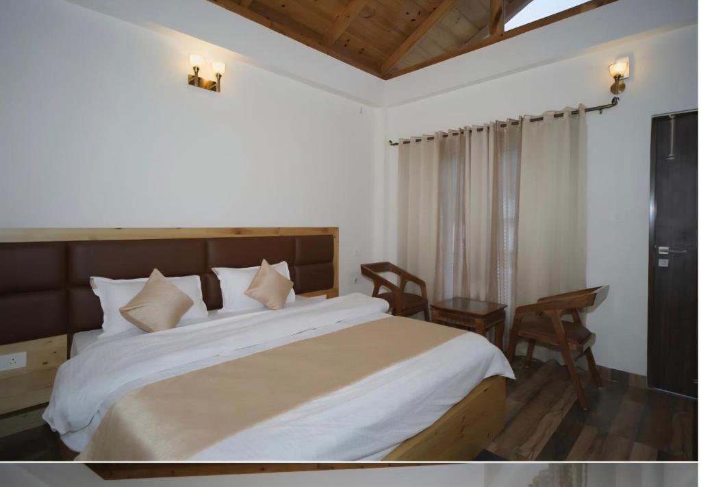 Un dormitorio con una cama grande y una mesa. en Aesquire Hotel, en Bhimtal