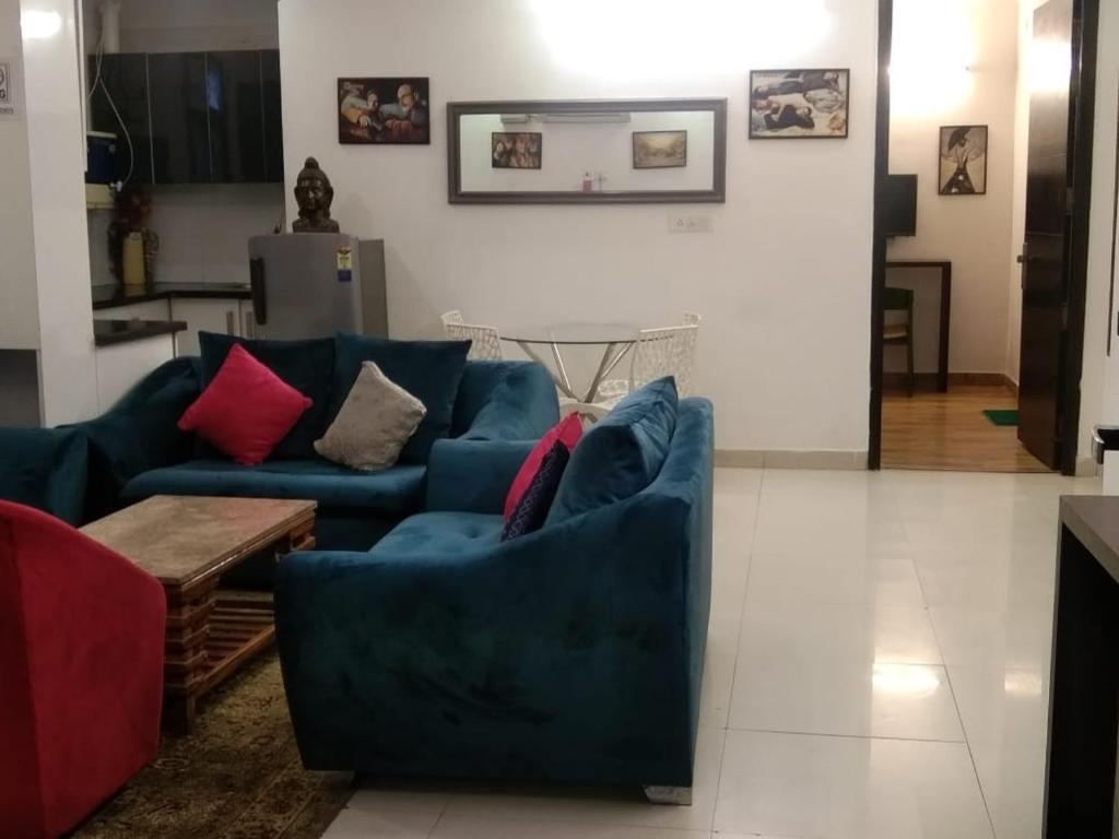 a living room with two blue couches and a table at Prestige Apartments in New Delhi