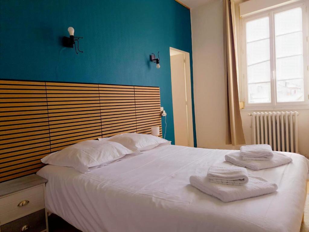a bedroom with a white bed with towels on it at L'Entracte in Saint-Paul-du-Bois