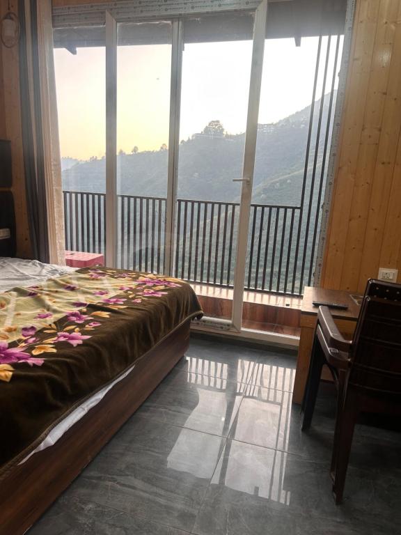 a bedroom with a bed and a desk and large windows at 3 H Homestay in Mussoorie