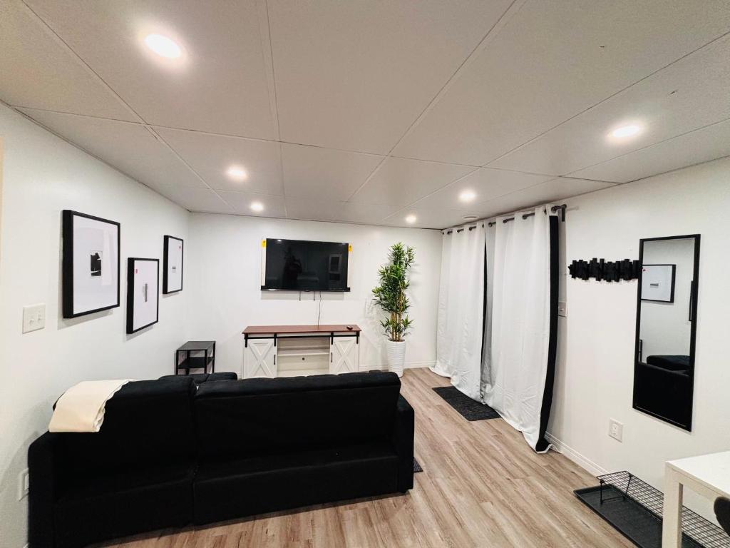 ein Wohnzimmer mit schwarzem Sofa und Fernseher in der Unterkunft Tovah in Winnipeg