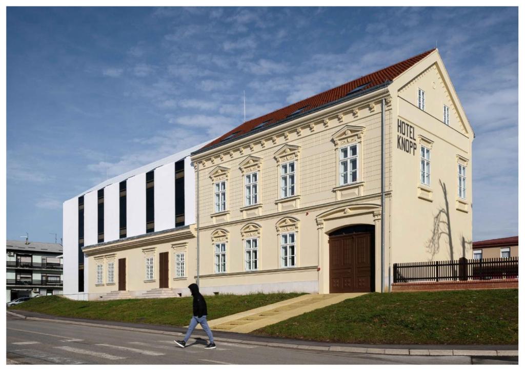 eine Person, die vor einem großen Gebäude läuft in der Unterkunft Heritage Hotel Knopp in Novska