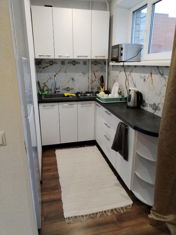 a kitchen with white cabinets and a white rug at Studio Art in Sillamäe