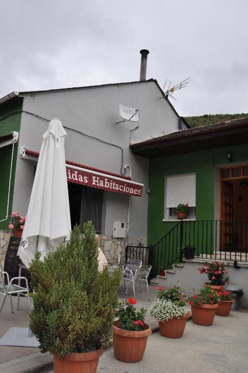 a restaurant with an umbrella and chairs and plants at Casa Polín in Las Herrerías