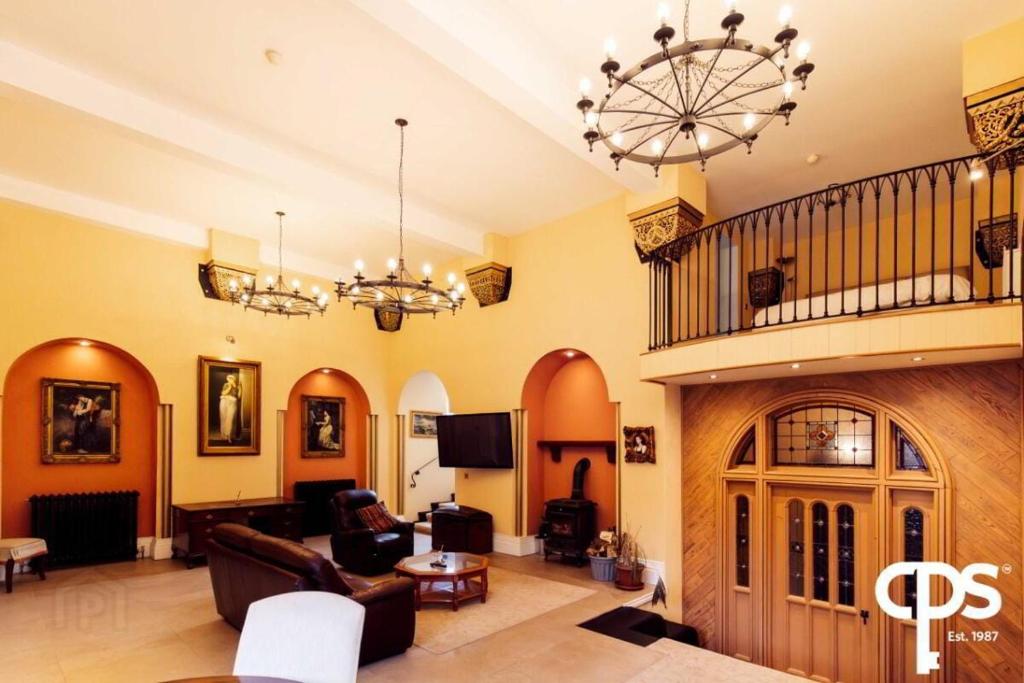 a large living room filled with furniture and a chandelier at Bastian Gate Gosford Castle 