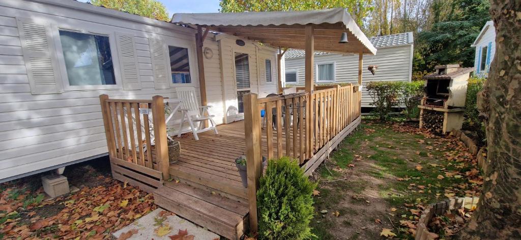 una casa con terraza de madera junto a una casa en Mobil-home de Ludo, en Ivry-la-Bataille