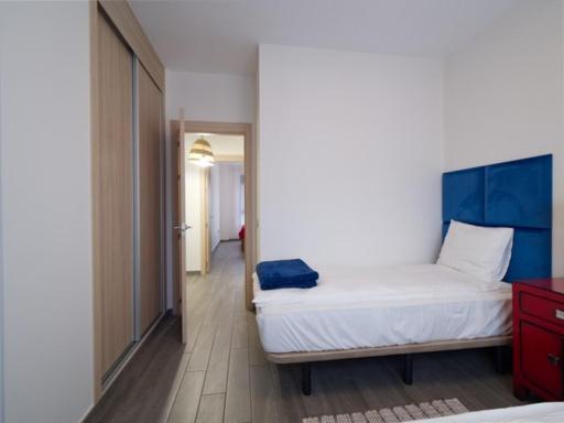 1 dormitorio con cama blanca y cabecero azul en Sunny Luxury Apartment with two great sunny - level terraces, two swimming pools, in a new complex Pueblo Majorero, close to Fuerteventura Golf Club, next to the beach , Atlantico Shopping Mall and casino in Caleta de Fuste, en Caleta de Fuste