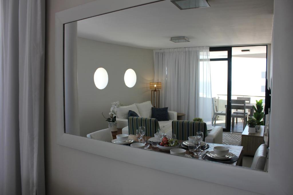 einen Spiegel im Wohnzimmer mit Esszimmer in der Unterkunft Luxurious 3-bedroom Bloubergstrand Cape Town beachfront apartment with stunning sea and beach view in Cape Town