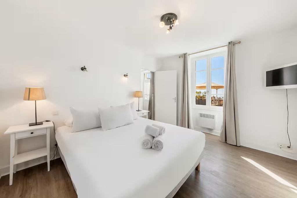 ein weißes Bett mit einem Paar Schuhe darauf in der Unterkunft Bord De L'Eau 3 et 6 in Cancale