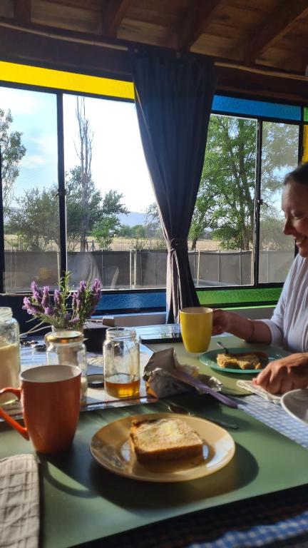 a person sitting at a table with a plate of food at Casa de campo boutique a 18 minutos de Merlo in Cortaderas