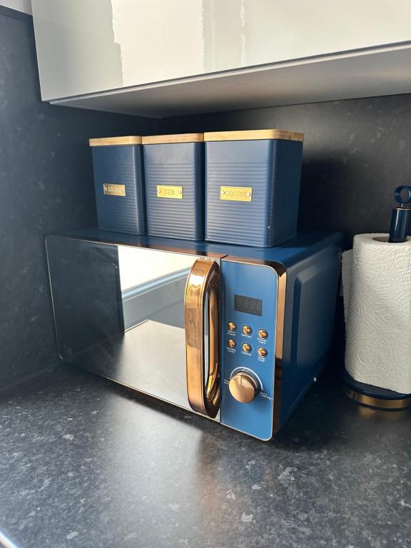 Un microondas azul sobre un estante con cajas azules. en Enfield Contractor Base With Games Room, en Brimsdown Station