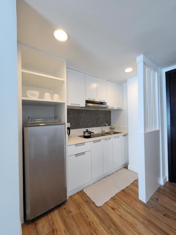 a kitchen with white cabinets and a stainless steel refrigerator at Comfy En-Suite Room in Kota Kinabalu