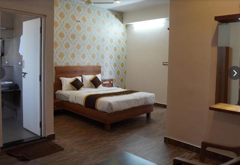 a bedroom with a large bed and a bathroom at Hotel Janani Mansion in Mysore